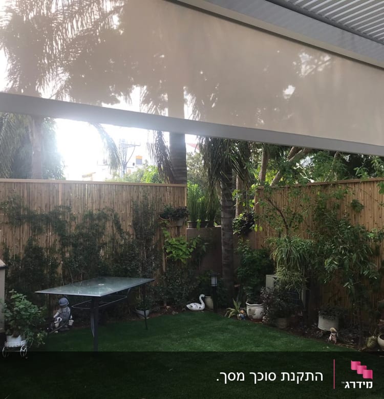 סוכך בד בהיר תלוי מעל גינה ירוקה
